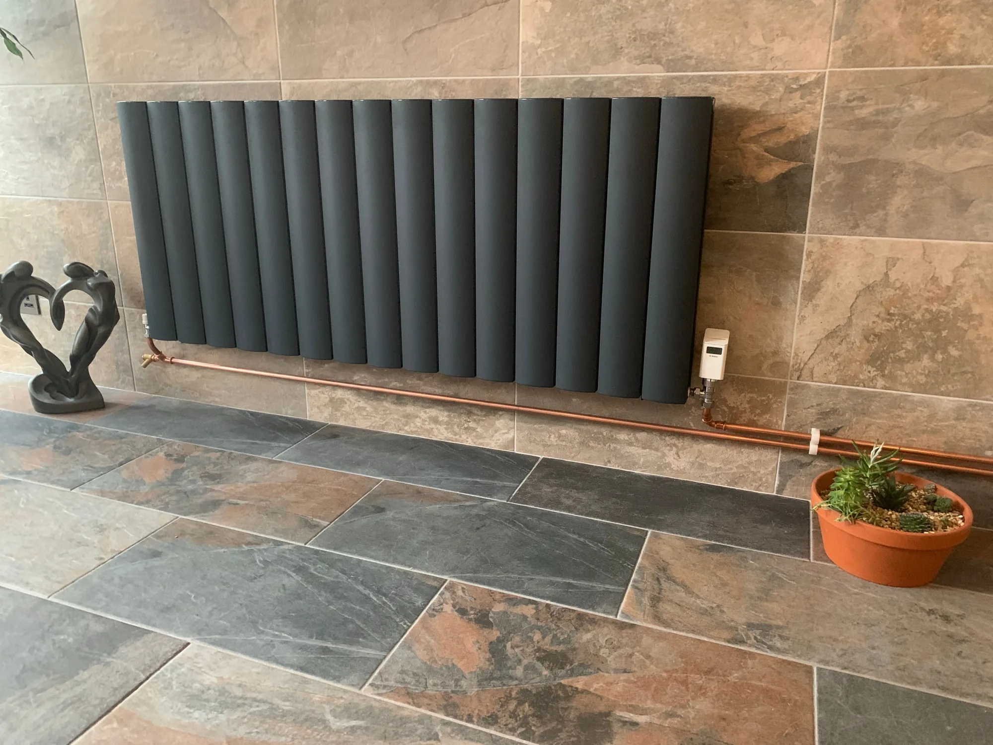 Designer radiator with neat polished copper pipework fitted by PARAGAS